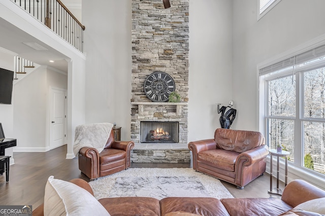 living area with a fireplace, a high ceiling, baseboards, and wood finished floors