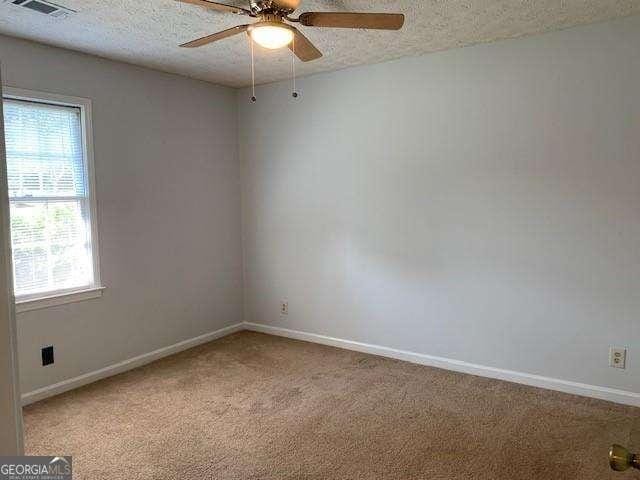 unfurnished room featuring a textured ceiling, baseboards, and light carpet