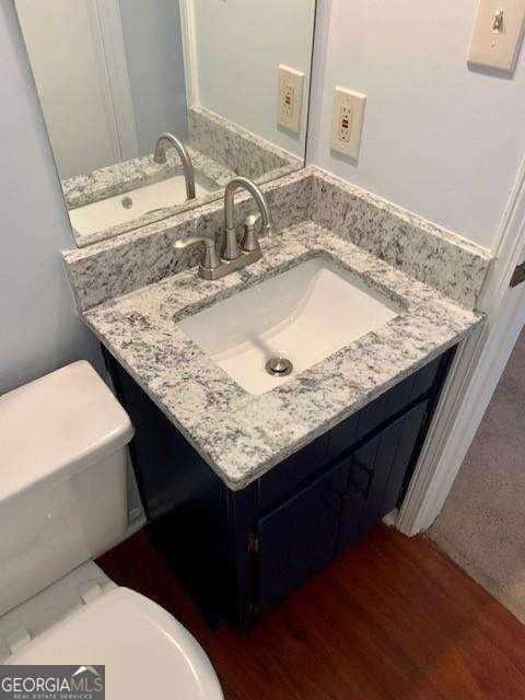 bathroom with toilet, wood finished floors, and vanity