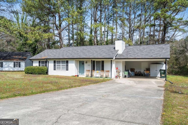 single story home featuring a front lawn, a carport, driveway, and a chimney