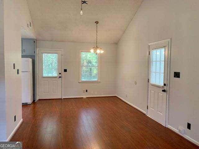 foyer with dark wood-style floors, baseboards, an inviting chandelier, and vaulted ceiling