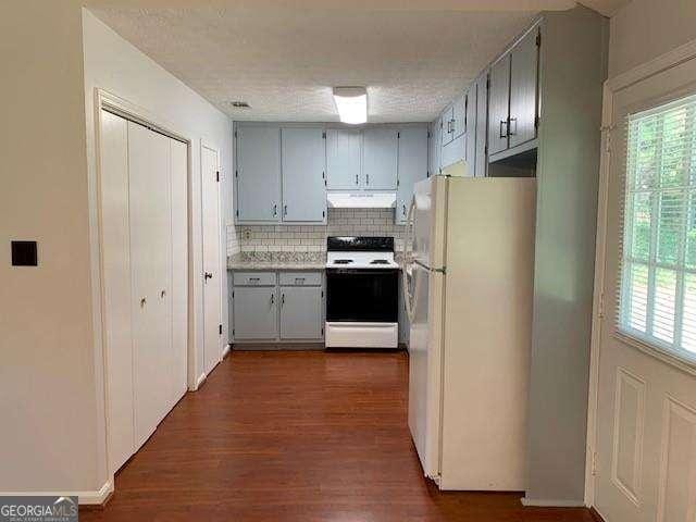 kitchen featuring tasteful backsplash, ventilation hood, freestanding refrigerator, dark wood-style floors, and electric range