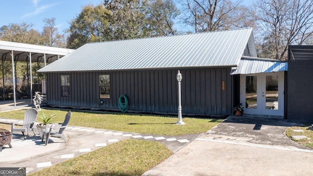 view of property exterior featuring metal roof, french doors, board and batten siding, and a fire pit