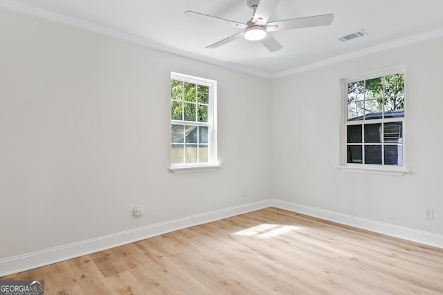 spare room with visible vents, ornamental molding, light wood-style floors, baseboards, and a ceiling fan