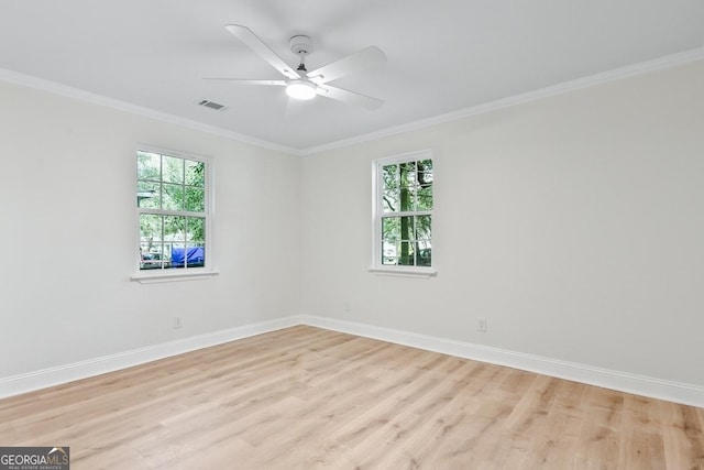 unfurnished room with baseboards, visible vents, a wealth of natural light, and ornamental molding