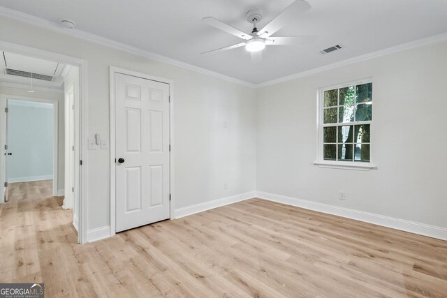 unfurnished room featuring visible vents, attic access, light wood-style flooring, and crown molding