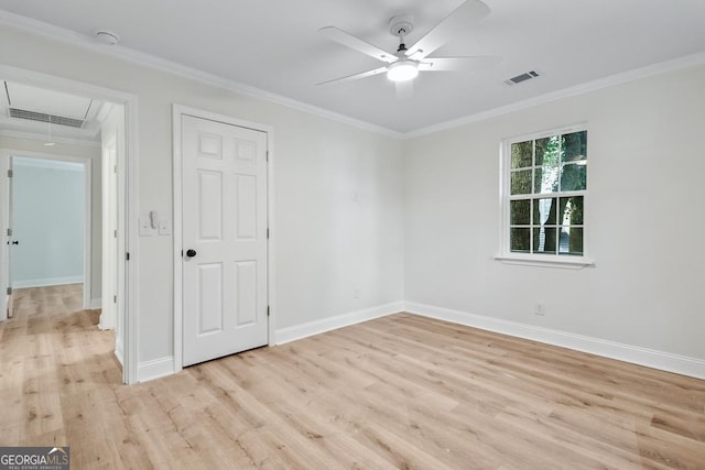 empty room with light wood-style floors, a ceiling fan, attic access, and visible vents