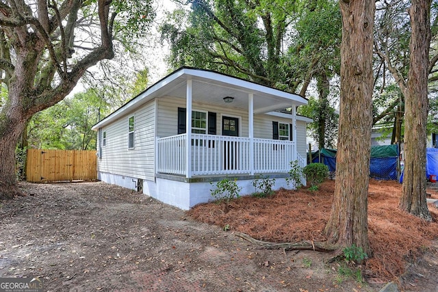 view of front of house featuring crawl space, covered porch, driveway, and fence