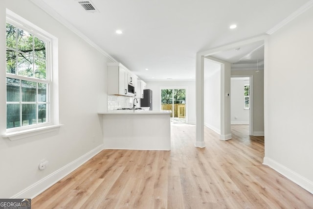 kitchen with crown molding, tasteful backsplash, white microwave, and visible vents