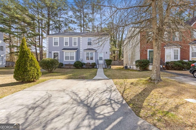 colonial-style house featuring a front yard and central air condition unit