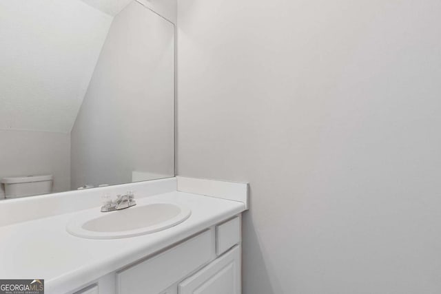 half bathroom featuring toilet, a textured ceiling, vanity, and lofted ceiling