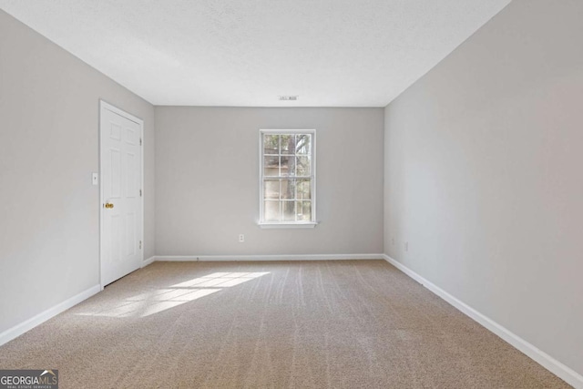 carpeted spare room featuring visible vents and baseboards
