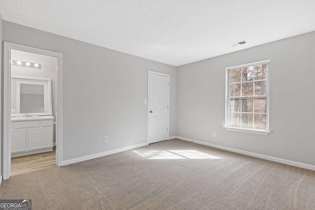 unfurnished bedroom with visible vents, baseboards, carpet, and ensuite bath