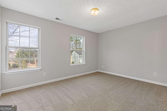 carpeted empty room with visible vents, baseboards, and a textured ceiling