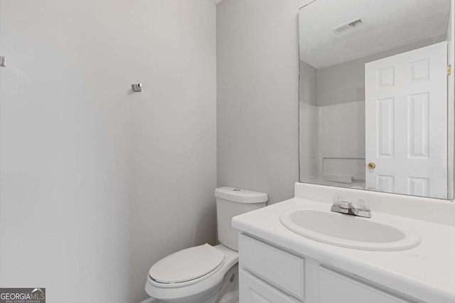 bathroom featuring toilet, vanity, and visible vents