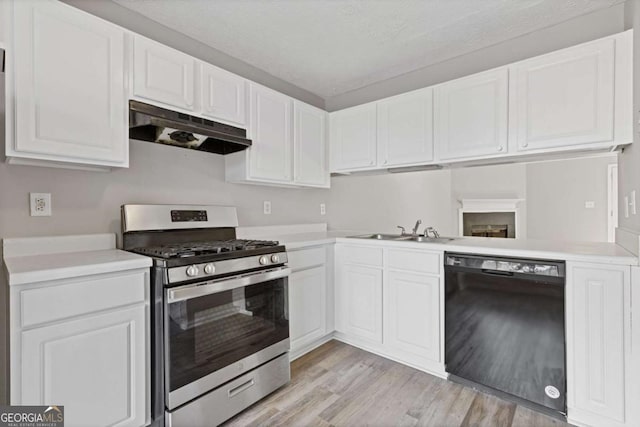 kitchen featuring white cabinets, black dishwasher, light countertops, under cabinet range hood, and gas stove