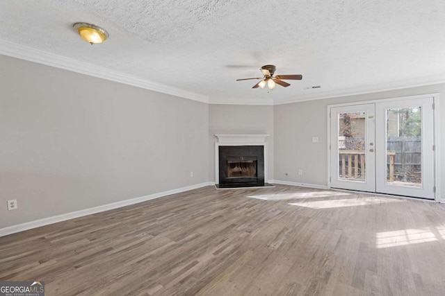 unfurnished living room featuring baseboards, ornamental molding, ceiling fan, wood finished floors, and french doors