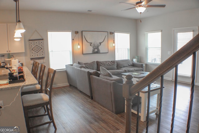 living room featuring baseboards, dark wood-style flooring, and ceiling fan