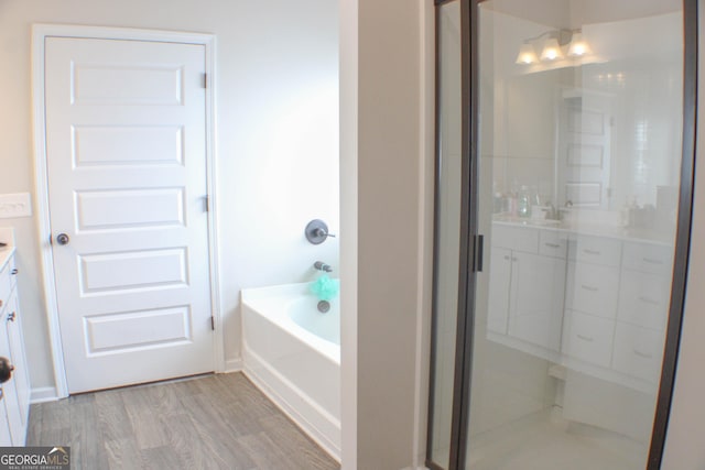 full bathroom featuring a shower with shower door, vanity, a garden tub, and wood finished floors