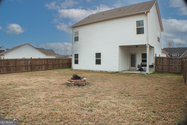 rear view of house with a yard, a patio, a fenced backyard, and an outdoor fire pit