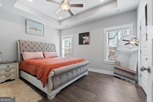 bedroom with a tray ceiling, recessed lighting, wood finished floors, and baseboards