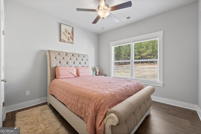 bedroom with visible vents, a ceiling fan, baseboards, and wood finished floors