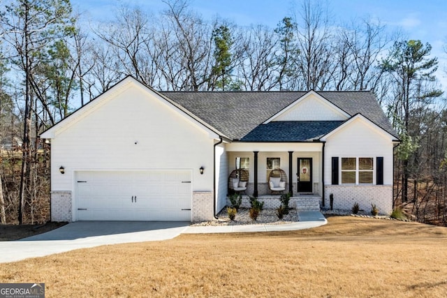 view of front facade with driveway, a porch, an attached garage, a front yard, and brick siding