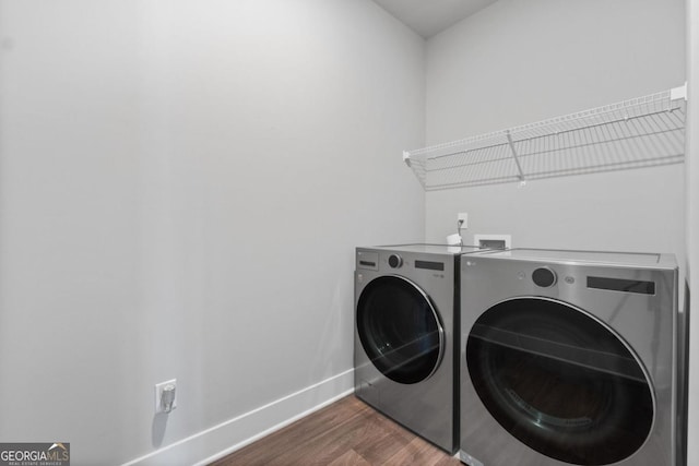 clothes washing area with baseboards, dark wood finished floors, laundry area, and washer and clothes dryer