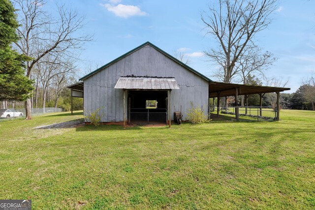 view of pole building with a carport, a lawn, and fence