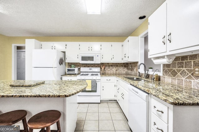 kitchen featuring a sink, white appliances, light stone counters, and white cabinetry