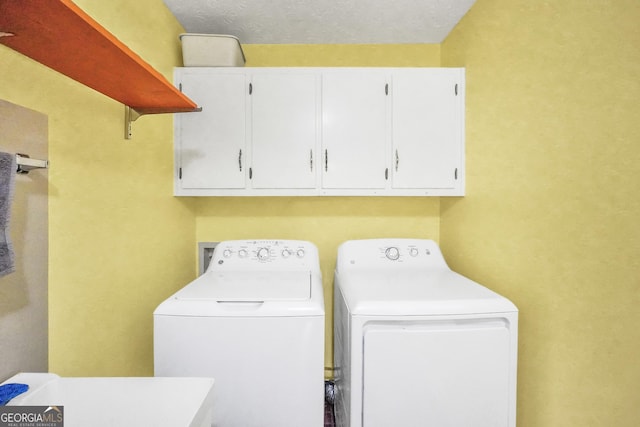 laundry room featuring cabinet space, a textured ceiling, and washer and clothes dryer