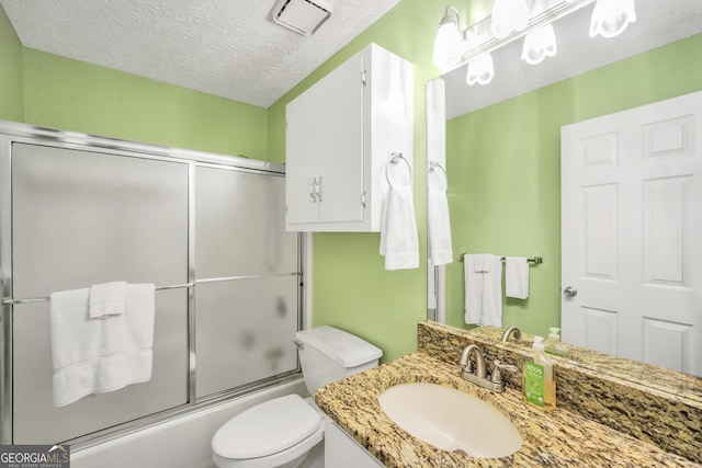 bathroom with vanity, visible vents, shower / bath combination with glass door, a textured ceiling, and toilet