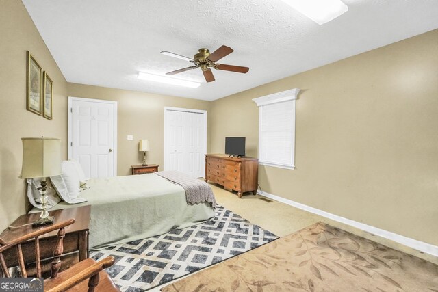 carpeted bedroom with a closet, a textured ceiling, baseboards, and a ceiling fan