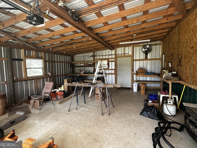 misc room featuring a workshop area, concrete floors, and metal wall