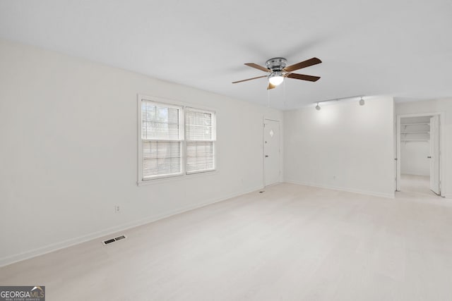 spare room with baseboards, visible vents, light wood-style flooring, ceiling fan, and track lighting