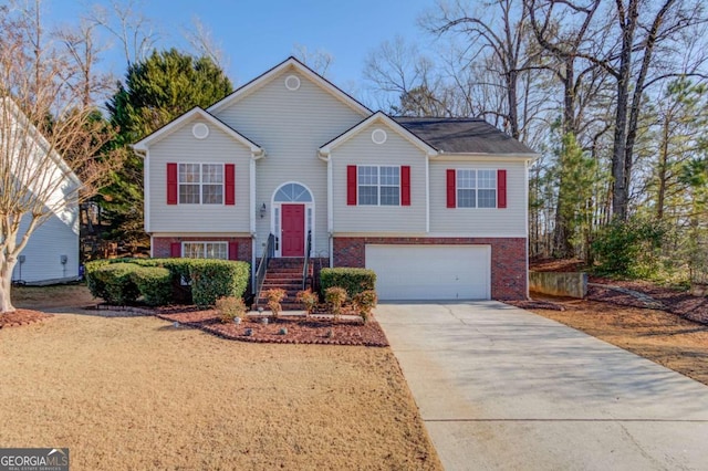 raised ranch featuring a garage, brick siding, and concrete driveway