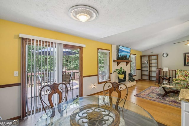 dining area featuring baseboards, a textured ceiling, lofted ceiling, and wood finished floors