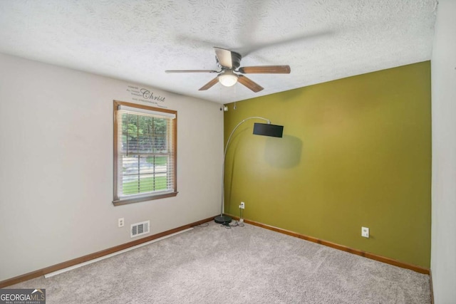 empty room with carpet, visible vents, baseboards, ceiling fan, and a textured ceiling