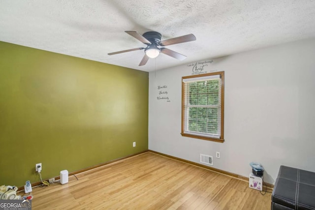 spare room with baseboards, visible vents, a textured ceiling, and light wood-style floors