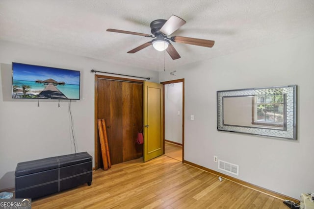 unfurnished bedroom with visible vents, baseboards, ceiling fan, light wood-style floors, and a textured ceiling