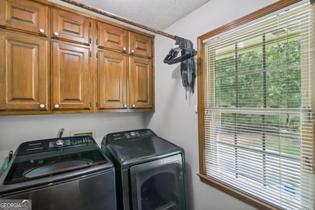 laundry area with a textured ceiling, cabinet space, and washer and clothes dryer