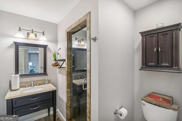 bathroom featuring a stall shower, toilet, vanity, and baseboards