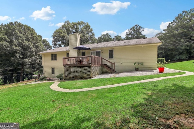 rear view of house featuring a lawn, a chimney, and a deck