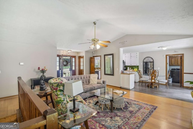 living room with wood finished floors, a ceiling fan, baseboards, and vaulted ceiling