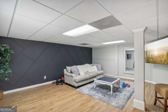 living area with a paneled ceiling, baseboards, and wood finished floors