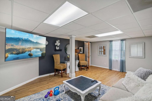 living room featuring baseboards, a paneled ceiling, and wood finished floors