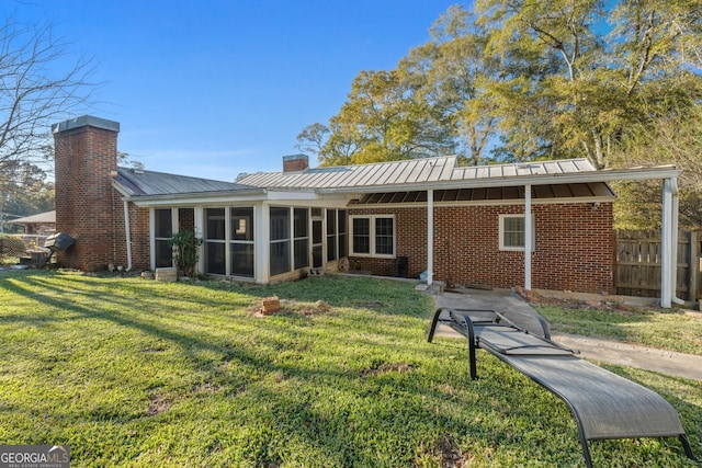 rear view of house featuring brick siding, a lawn, a chimney, and a sunroom