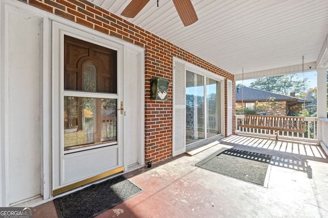 entrance to property with brick siding, covered porch, and ceiling fan