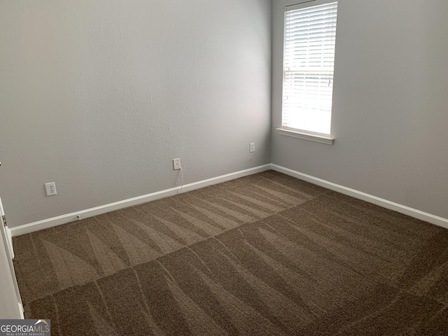 unfurnished room with baseboards and carpet