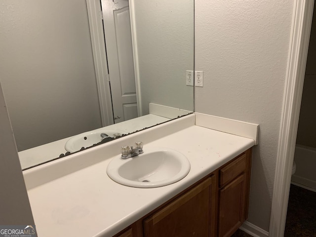 bathroom featuring toilet, vanity, and a textured wall